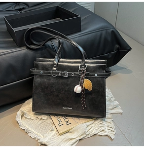Macro shot of vintage black leather tote bag with silver buckle and baseball glove charm