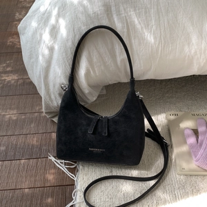 Close-up of black matte leather hobo bag with silver lettering on soft plush carpet