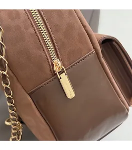 Detail view of smooth metal zipper and woven gold chain on the brown leather backpack