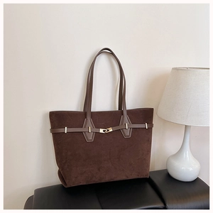 Detail of dark brown suede tote bag with elegant golden hardware in warm ambient lighting