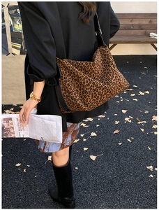 Outdoor street view of a large leopard print tote bag with black wide straps on model
