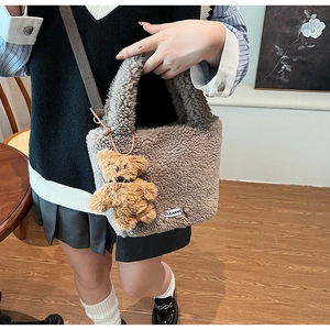 Detailed close-up of brown plush bucket bag featuring cute bear charm and shoulder strap