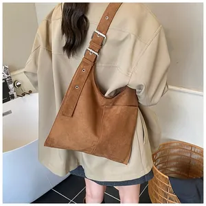 Detail of suede bucket bag featuring wide shoulder strap with silver buckle and eyelets