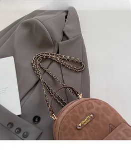 Brown suede half-moon backpack with metal chain strap and golden fashion logo detail