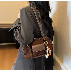 Detail of vintage suede shoulder bag with wood bead charm and dark coffee leather trim