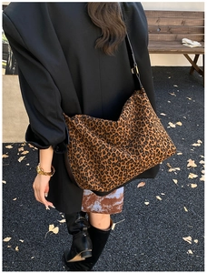 Detail of a large leopard print tote bag styled in a casual outdoor autumn setting
