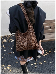 Outdoor lifestyle shot of a soft leopard print canvas tote bag carried by a model