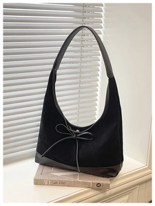 Detail of black suede tote bag with bow knot on a window sill with natural light