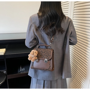 Détail du sac léopard avec boucles argentées et pendentif en forme d'ours brun