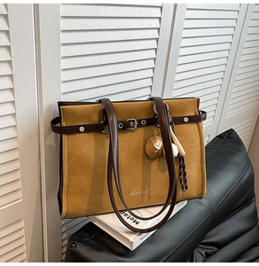 Detail of vintage suede tote bag with leather strap and strawberry charm accent