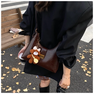 Close-up of a dark brown glossy leather underarm bag with a vintage gold metal lock buckle