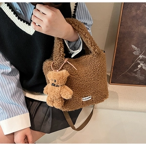Detail of brown teddy fleece bucket bag with plush bear charm and brand label