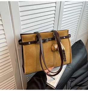 Detail of vintage mustard suede tote bag featuring a pinecone charm and leather strap