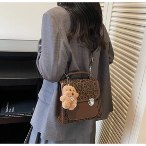 Detail of leopard print messenger bag with silver twist lock and plush bear charm