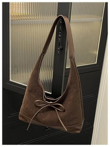 Detail of dark brown tote bag with leather bow hanging on a glass cabinet door