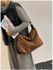 Detail of leopard print hobo bag showing black wide shoulder strap and gold buckle