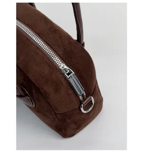 Detail von Silber-Reißverschluss und Ring an dunkelbrauner Bowling-Tasche aus Wildleder