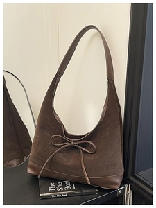Detail of dark brown tote bag with suede texture and decorative bow for women