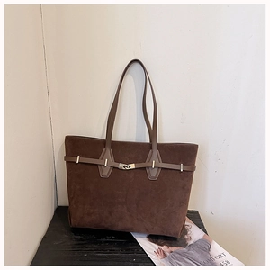 Detail view of dark brown suede tote bag with golden metal buckle and leather strap