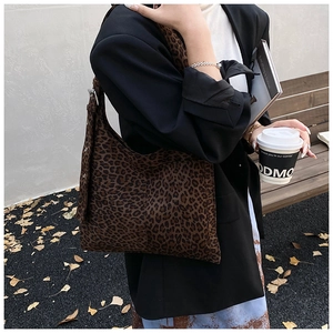 Close-up of leopard print suede bucket bag featuring metal buckle and eyelet strap details