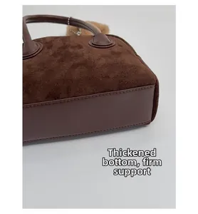 Detailansicht des verstärkten Bodens und Wildledermaterials der braunen Boston-Tasche