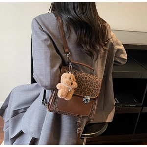 Détail du sac à bandoulière léopard avec pendentif ours en peluche porté par le mannequin