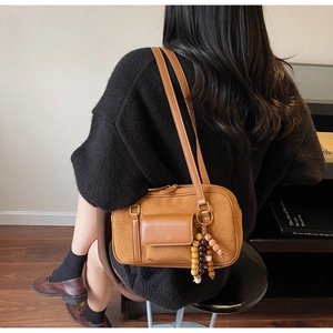 Detail of suede Boston bag with ethnic bead charm and leather patch pocket in brown