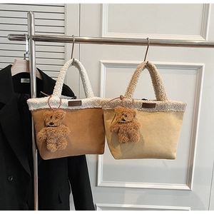 Detail view of suede tote bags with white faux shearling trim and bear pendants
