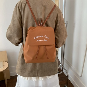 Detail of caramel fashion backpack featuring Honey Cute text and drawstring closure