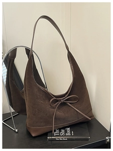 Detail of vintage brown suede tote bag with a decorative bow and smooth leather accents