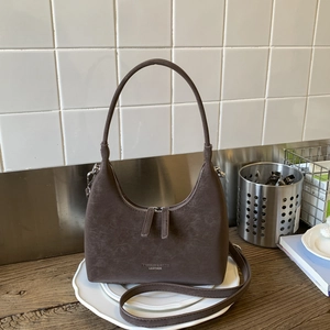 Close-up of vintage dark brown crescent bag with premium leather texture and dual metal zippers