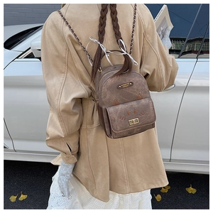 Detailed macro view of a vintage brown mini backpack with cat-ear design and metal chain strap