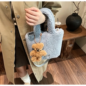 Detail of light blue faux shearling bucket bag with cute brown bear charm and logo tag