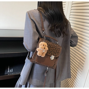 Detail of leopard print crossbody bag with silver twist lock and cute teddy bear charm