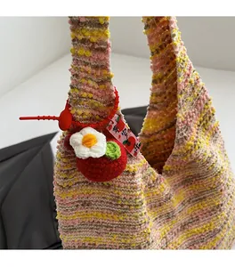 Detail of color-block knit tote bag featuring handmade apple and flower bag charms
