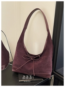 Detail of burgundy suede tote bag featuring a bow tie knot and smooth leather base