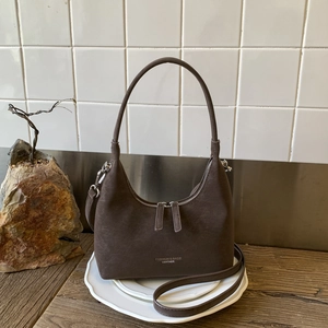 Detail of dark brown leather crescent bag with dual silver zippers and adjustable strap