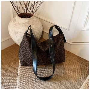 Detail of leopard print tote bag with wide black leather strap and gold metal eyelets