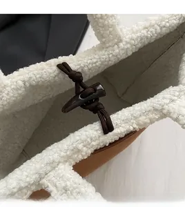 Close-up of white fuzzy tote bag featuring a vintage dark brown toggle button closure