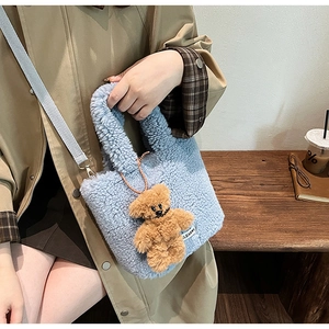 Detail showing soft light blue faux shearling bucket bag with a cute teddy bear charm