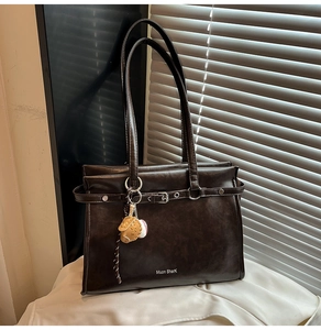 Detail view of coffee brown retro tote bag featuring baseball glove charm and metal buckle