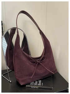Detail of burgundy suede tote bag featuring elegant bow tie and premium leather patchwork