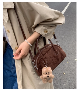 Detailed texture of dark brown suede Boston bag with silver hardware and puppy charm