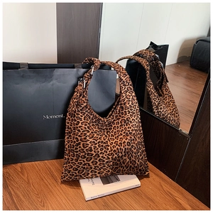 Detail of trendy leopard print tote bag with large capacity on a wooden surface