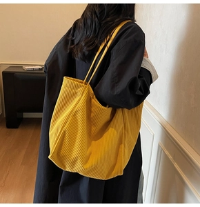 Gros plan sur la texture du sac cabas en velours côtelé jaune vif et détails nervurés