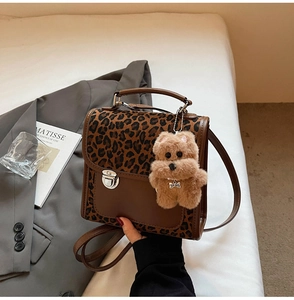 Détail d'un sac bandoulière léopard avec fermoir argenté et porte-clés ours