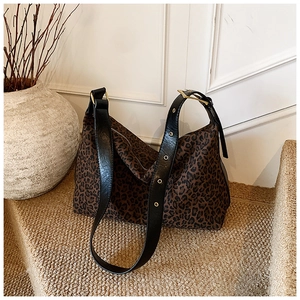 Detail of leopard print tote bag with black leather strap and gold metal eyelets