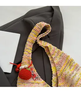 Close-up of rainbow crochet tote bag featuring a red apple pendant and knit texture