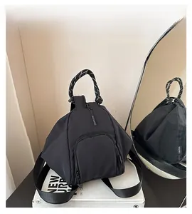 Detail of black nylon triangular backpack with black and white rope handle design