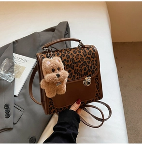Détail du sac léopard avec charm chien en peluche et bandoulière sur décor esthétique
